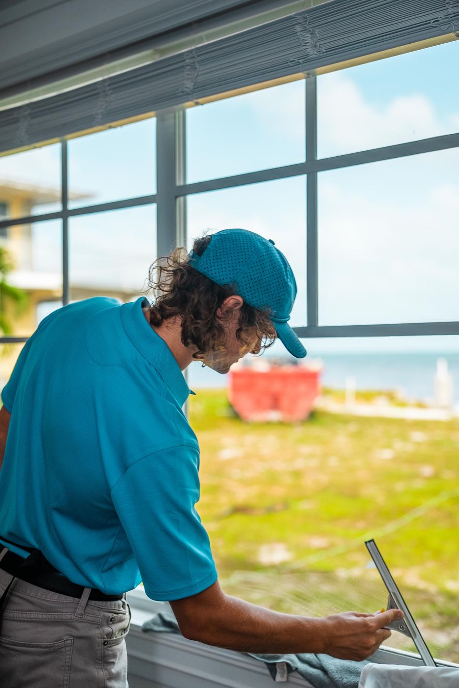 Technician squeegeeing an interior window that looks out on green grass and open water